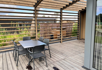 Buitenterras aan Cube Split Hottub lodge bij EuroParcs Enkhuizer Strand in Nederland, met tafel en stoelen.