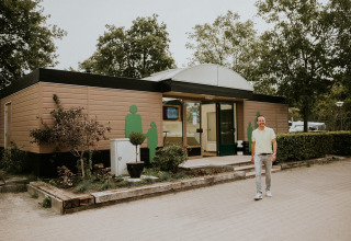 Man wandelt voor het sanitair gebouw op Camping Si-Es-An in Overijssel, Nederland, tijdens de vakantie.