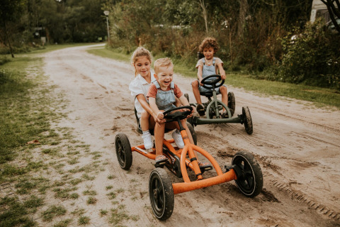 Kinderen rijden op skelters op een zandweg in het vakantiepark Camping Si-Es-An in Overijssel, Nederland.