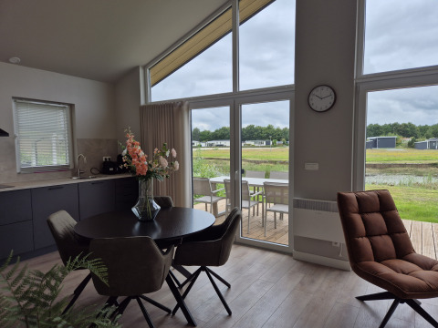 Salon et salle à manger modernes au lodge Type Dommel, De Tien Heugten, Pays-Bas, vue sur terrasse et étang.