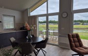 Modern living and dining area inside Type Dommel lodge at De Tien Heugten, Netherlands, with terrace view.
