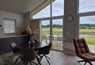 Salon et salle à manger modernes au lodge Type Dommel, De Tien Heugten, Pays-Bas, vue sur terrasse et étang.