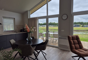 Modern living and dining area inside Type Dommel lodge at De Tien Heugten, Netherlands, with terrace view.
