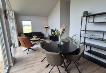 Modern lodge interior at Type Dommel, De Tien Heugten, Netherlands, with large windows and stylish furniture.