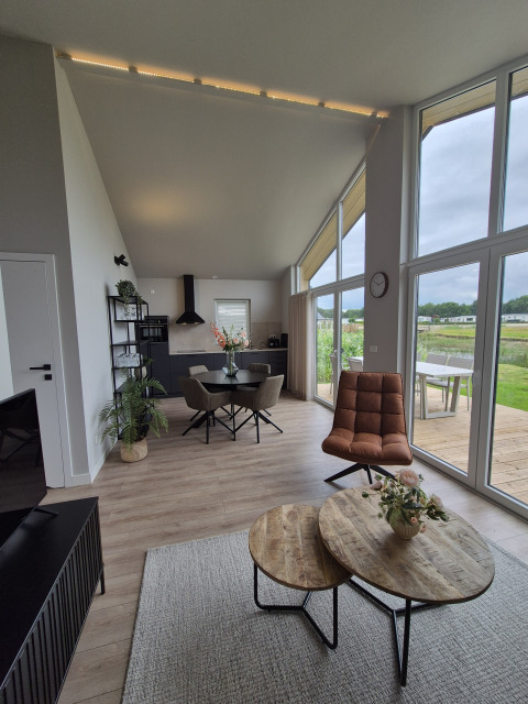Intérieur moderne d'un lodge avec grandes fenêtres et meubles en bois à Type Dommel, De Tien Heugten, Pays-Bas.