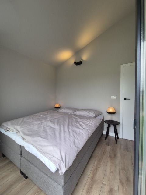 Chambre lumineuse et moderne dans le lodge Type Dommel à De Tien Heugten, Pays-Bas, avec un grand lit double.