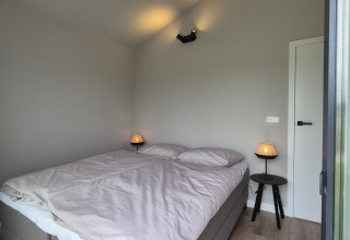 Chambre lumineuse et moderne dans le lodge Type Dommel à De Tien Heugten, Pays-Bas, avec un grand lit double.