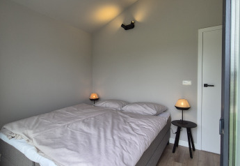 Bright, modern bedroom at Type Dommel lodge in De Tien Heugten, Netherlands, featuring a large double bed.