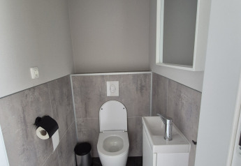 Modern bathroom in Type Dommel lodge at De Tien Heugten in the Netherlands, featuring a toilet and sink.