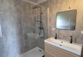 Modern bathroom with walk-in shower, double sink and mirror at Type Dommel lodge, De Tien Heugten, Netherlands.