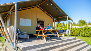 Une famille prend le petit-déjeuner devant leur tente safari Lodgetent 4 par une belle journée ensoleillée.