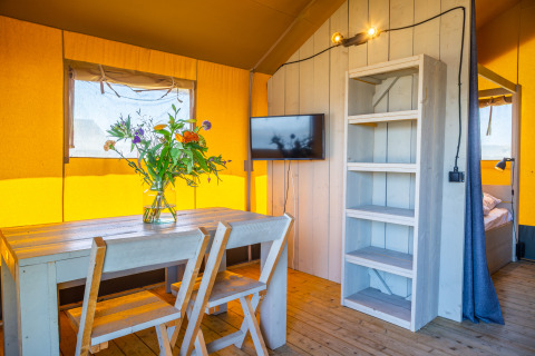 Interior view of Lodgetent 4 at Zuiderzee, Netherlands, featuring a wooden table, chairs, and warm decor.