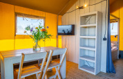 Interior view of Lodgetent 4 at Zuiderzee, Netherlands, featuring a wooden table, chairs, and warm decor.