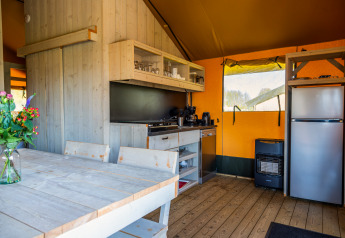 Interieur van safari Lodgetent 4 bij Zuiderzee, Nederland, met keuken, eettafel en moderne voorzieningen.