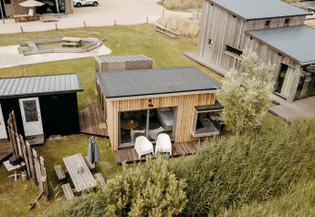 Luchtbeeld van de Solglimt 4 Pers. lodge met houten gevels, terrassen en grasrijke omgeving bij duinen.