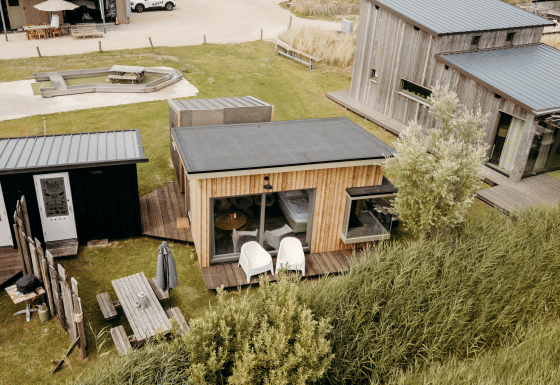 Vue aérienne du lodge Solglimt 4 Pers. : façades bois, terrasses et espaces verts près des dunes.