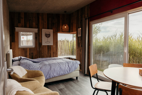 Cozy bedroom in Solglimt 4 Pers at Duynpark Het Zwanenwater, Netherlands, with a bed, chairs, and large windows.