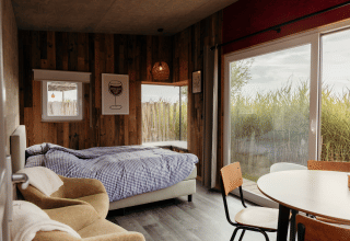 Acogedor dormitorio en Solglimt 4 Pers de Duynpark Het Zwanenwater, Países Bajos, con cama y grandes ventanales.
