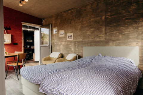 Chambre de lodge moderne avec lit double, fauteuils et déco rustique au Duynpark Het Zwanenwater, Pays-Bas.