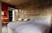 Modern lodge bedroom with double bed, armchairs, and rustic decor at Duynpark Het Zwanenwater, Netherlands.
