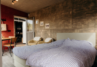 Habitación de lodge moderna con cama doble, sillones y decoración rústica en Duynpark Het Zwanenwater, Países Bajos.