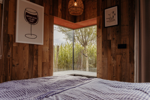 Interior view of Solglimt 4 Pers lodge with wood walls and nature view, Duynpark Het Zwanenwater, Netherlands.