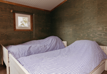 Twee eenpersoonsbedden met blauw geruit beddengoed in Solglimt 4 Pers, Duynpark Het Zwanenwater, Nederland.