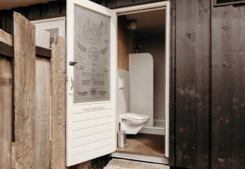 Foto di un bagno di una lodge con porta aperta, wc sospeso e pareti esterne in legno scuro.