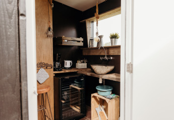 Kleine, gezellige lodgekeuken met houten planken, een stenen wasbak en veel natuurlijk licht.