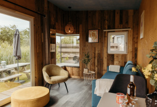 Acogedora cabaña Solglimt 2 Pers. en Duynpark Het Zwanenwater con paredes de madera y vista al exterior.