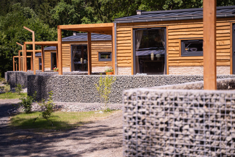 Houten lodges en stenen muren bij Panorama Lodge, Pressegger See, Oostenrijk, omringd door natuur.
