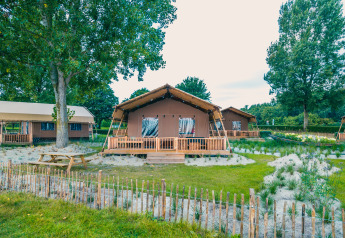 Safari telt Lodgetent Haven 4 ved Zuiderzee i Holland omgivet af træer, sand og rustik indhegning.