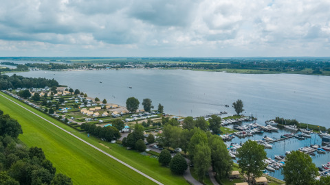 View of Zuiderzee in the Netherlands showing safari tents, a campground, and marina by the lake under clouds.
