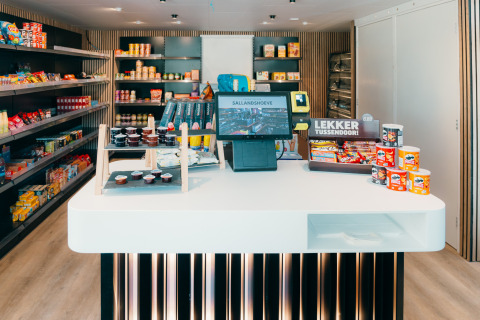 Pequeña tienda en un alojamiento glamping con snacks, mostrador de pago y estantes llenos de productos.