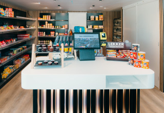 Piccolo negozio in una sistemazione glamping con snack, banco cassa e scaffali pieni di prodotti.