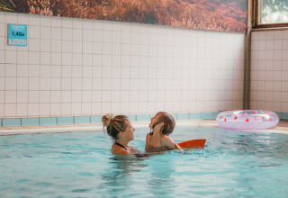 Madre e hijo disfrutan nadando en la piscina cubierta de un alojamiento glamping, con flotador al fondo.