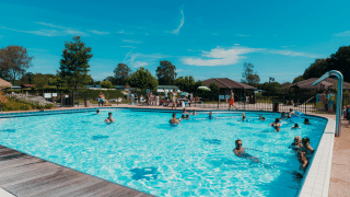 Piscina al aire libre con veraneantes felices en el parque vacacional De Boshoek en Gelderland, Países Bajos.