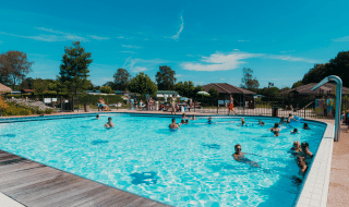 Piscina al aire libre con veraneantes felices en el parque vacacional De Boshoek en Gelderland, Países Bajos.