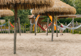 Kindgerechter Bereich mit Hängematten und Strohdächern im Sand im Ferienpark De Boshoek, Gelderland.