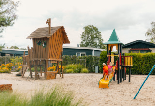 Niños jugando en un parque infantil con tobogán y casa de madera en De Boshoek, Gelderland, Países Bajos.
