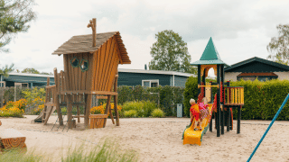 Niños jugando en un parque infantil con tobogán y casa de madera en De Boshoek, Gelderland, Países Bajos.