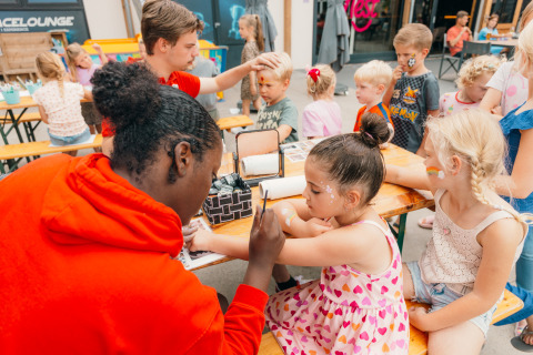 Niños disfrutan de pintacaras y actividades divertidas en mesas de Holiday park De Boshoek en Gelderland.