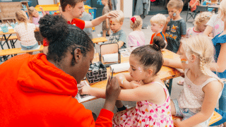 Niños disfrutan de pintacaras y actividades divertidas en mesas de Holiday park De Boshoek en Gelderland.