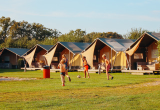 Bambini giocano a calcio davanti a tende glamping al parco vacanze De Boshoek, in Gelderland, Paesi Bassi.