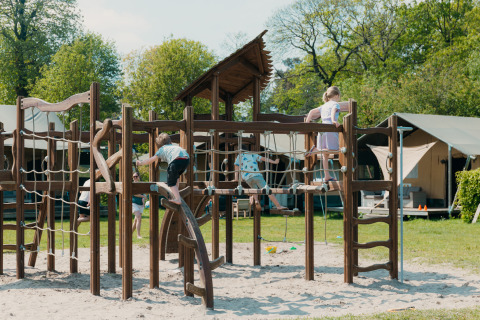 Kinder spielen auf einem großen Kletterspielplatz im Ferienpark De Boshoek, Gelderland, Niederlande.