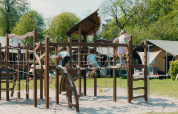 Children are climbing and playing on a wooden playground at Holiday park De Boshoek in Gelderland, Netherlands.