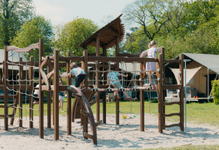 Børn leger på en stor legeplads med klatreudstyr i ferieparken De Boshoek, Gelderland, Holland.