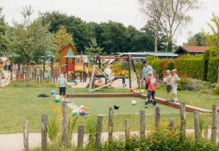Kinder spielen auf einem Spielplatz im Ferienpark De Boshoek in Gelderland, Niederlande, umgeben von Natur.