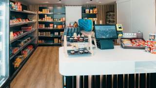 Un minimercado moderno en un parque de vacaciones glamping, estanterías llenas de snacks y caja registradora.