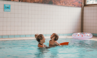 Madre e hija disfrutan en una piscina cubierta de un parque vacacional glamping, cerca de un flotador.